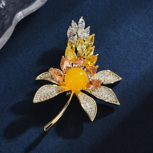 Elegant wheat leaf amber brooch with floral zircon inlay on a dark blue velvet background