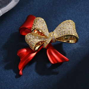 Elegante spilla a fiocco con cristalli bianchi e finitura rossa opaca su sfondo blu
