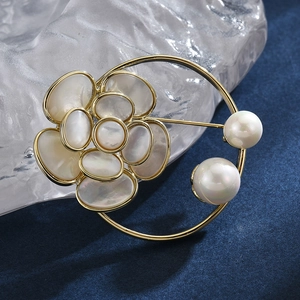 Broche fleur en nacre élégante avec perles et cadre doré sur fond texturé bleu