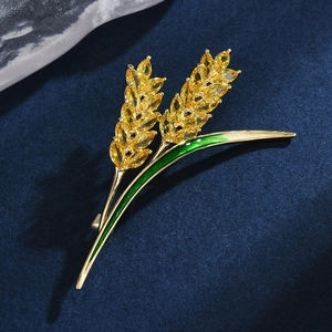 Spilla spiga di grano dorata con zirconi gialli e smalto verde su fondo blu materico