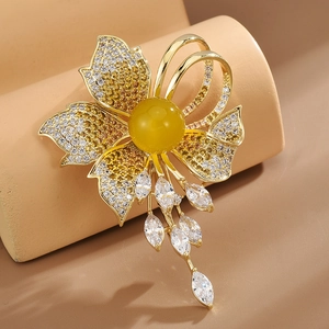 Floral brooch with yellow crystals, tassels, and gold metal on a display stand