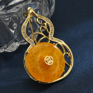 Elegant gold-tone wulu brooch with zircon inlay and amber-colored gemstone centerpiece