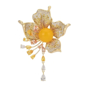 Detail of flower brooch with gradient pave zircon, amber center and tassel chains