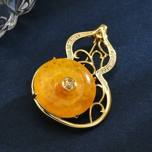 Elegant gold gourd brooch with yellow amber stone and zircon crystals on blue fabric