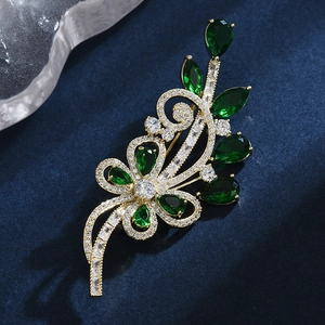 Élégante broche fleur dorée avec pierres vert émeraude et zircons cubiques brillants