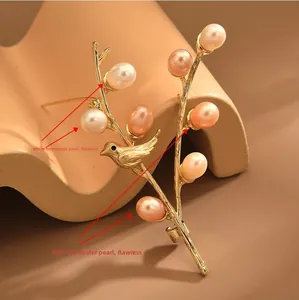 Macro shot of gold bird brooch with flawless white and pink freshwater pearls