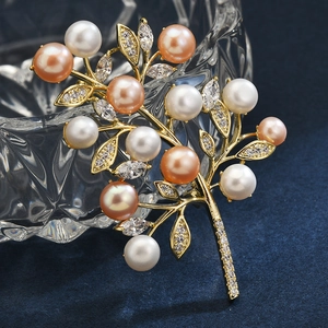 Exquisite gold twig brooch with multi-colored pearls and zircon crystals on blue background
