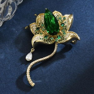 Elegant gold lotus brooch with green pear-shaped gemstone and cubic zirconia accents