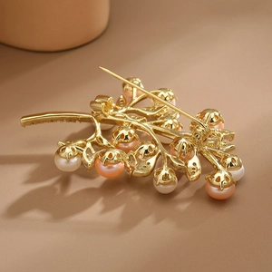 Elegant gold twig brooch with white and pink pearls showing the detailed back pin structure