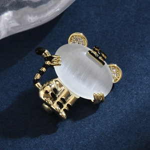 Golden tiger brooch with white cat eye stone and enamel details on blue velvet