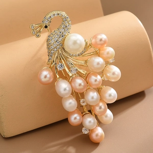 Exquisite golden peacock brooch with freshwater pearls and sparkling crystals on a pedestal