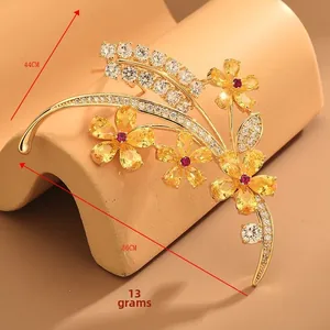 Vue détaillée d'une broche fleurie avec pierres jaunes et zircon rouge au centre