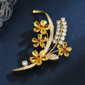Broche florale élégante avec zircons jaunes et pierre rouge sur velours bleu nuit