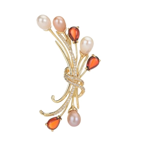 Élégante broche bouquet en or avec zircon rouge et perles d'eau douce sur fond blanc