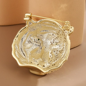 Macro view of gold tiger brooch showing matte texture and sparkling zircon inlay