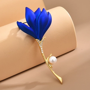 Elegant blue rose brooch with gold stem, zircons, and pearl detail on a pedestal