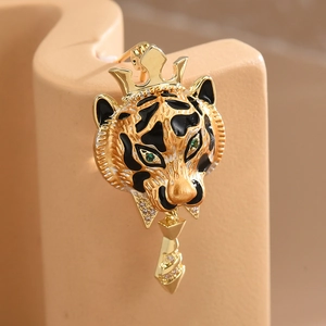 Macro detail of a golden tiger brooch with crown, green eyes and geometric pendant