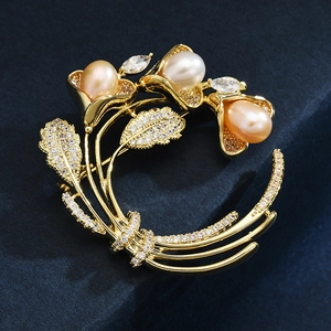 Detailaufnahme der goldenen Blumenbrosche mit Champagnerperlen und weißen Zirkonia