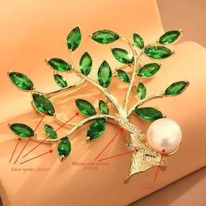 Close-up of tree brooch featuring green zircon leaves and a white freshwater pearl