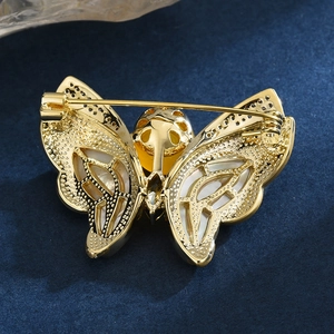 Broche papillon dorée avec zircons, ailes en nacre et ambre jaune sur velours bleu