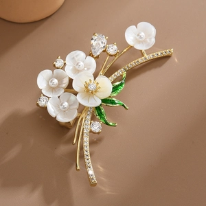 Broche florale élégante avec pétales en nacre blanche, feuilles émaillées et zircons
