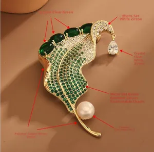 Close-up of elegant leaf brooch featuring green zircons, micro-inlay, and teardrop pearl