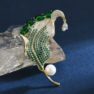 Elegant gold leaf brooch with green zircons and pearl drop on blue velvet base