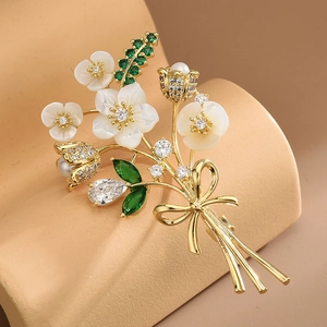 Broche bouquet floral doré avec pétales en nacre blanche et feuilles en zircon