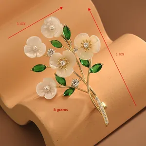 Macro detail of bouquet brooch with white mother of pearl petals and green stones