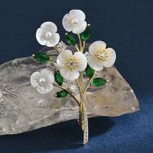 Elegant gold flower brooch with white shell petals, pearls and green zircon accents