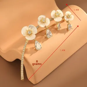 Detailed view of 7.0cm x 3.0cm gold floral brooch with white shells and zircon stones