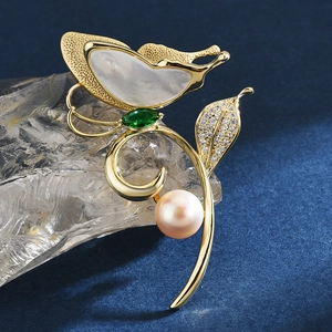 Elegant gold butterfly brooch with white shell wings, green gem, and round pearl