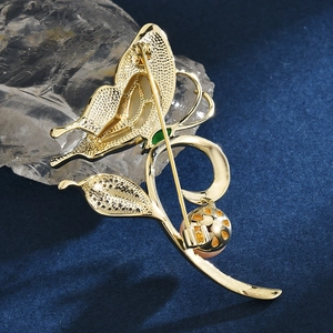 Elegant gold butterfly brooch featuring leaf design and a pink freshwater pearl accessory