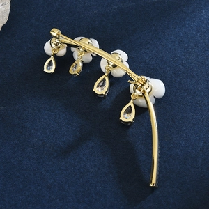 Elegant gold curved brooch with white flowers and sparkling pear-cut crystal charms