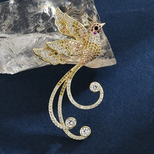 Elegant gold phoenix brooch with colorful crystals and white stones on dark textured base