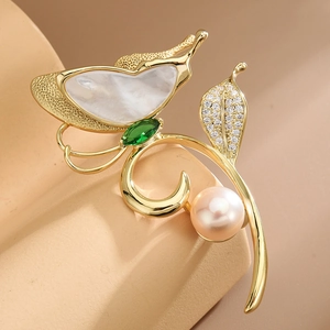 Elegant gold butterfly brooch with mother of pearl, green gemstone, and a white pearl accent