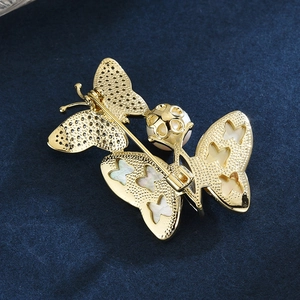 Broche papillon dorée élégante avec ailes en nacre blanche et une perle centrale raffinée