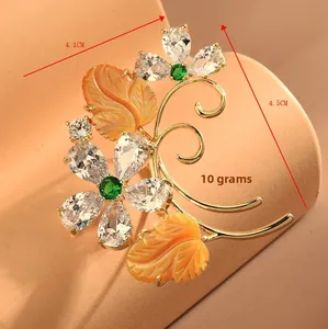 Macro detail of autumn leaf brooch with zircon floral petals and gold-tone finish