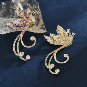 Elegant gold phoenix brooch with purple and champagne crystals on dark velvet