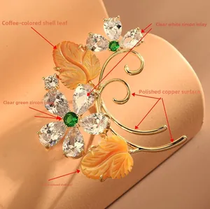 Close-up of golden branch brooch with shell leaves and zircon flowers on a warm pedestal