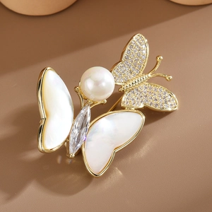Broche papillon élégante avec ailes en nacre blanche, base dorée et cristaux