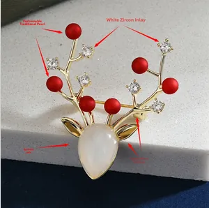 Détail de la broche élan avec perles rouges, zircone et jade blanc sur base dorée