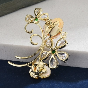 Rear view of gold flower brooch with zircon and shell detailing on a stone base