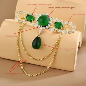 Detail der Vintage-Brosche mit grünen Steinen und eleganten goldenen Kettenquasten