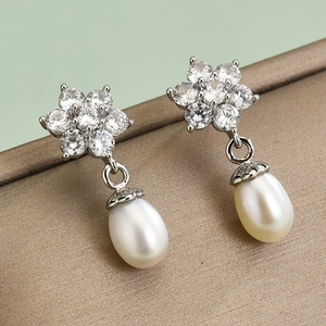 Elegant S925 silver pearl drop earrings with floral zircon clusters on a soft green background