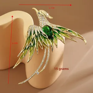 Dettaglio della spilla a fenice con smalto verde e placcatura in oro, misura 6,1cm x 6,6cm