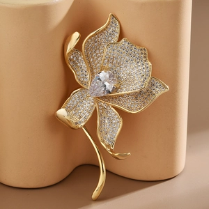 Macro shot of gold floral brooch with micro-pave zircons and pear-cut center stone