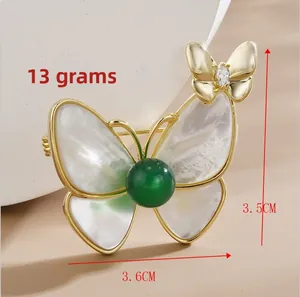 Détail d'une broche papillon en nacre avec perle verte et dimensions du produit