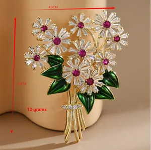Détail d'une broche florale avec zircons blancs, centre rouge et feuilles vertes