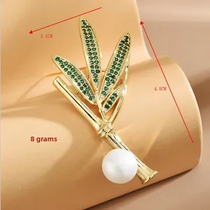 Vue détaillée d'une broche bambou avec cristaux verts et perle sur un support